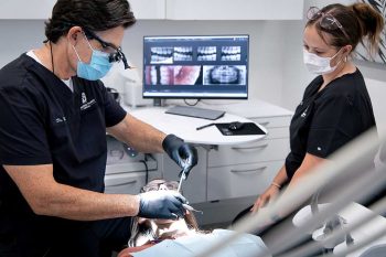 Dr. Baird and a Millcreek Family Dental team member examining a patients mouth