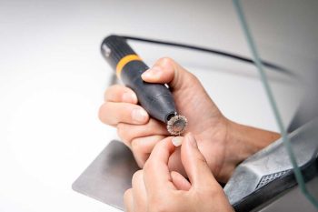 A Dremel with a rotary brush preparing to be used on a veneer